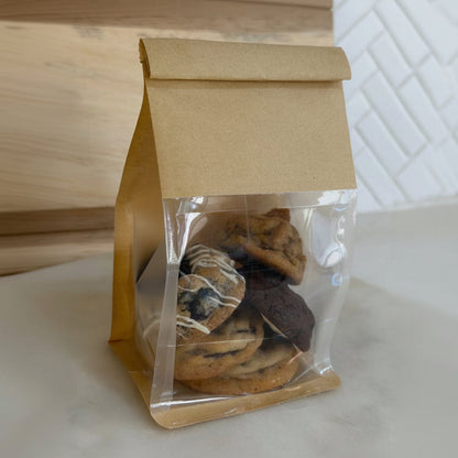 assorted chocolate chip cookies, set on a light countertop with a wooden and tiled background