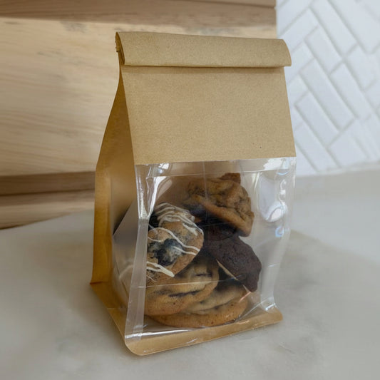 assorted chocolate chip cookies, set on a light countertop with a wooden and tiled background