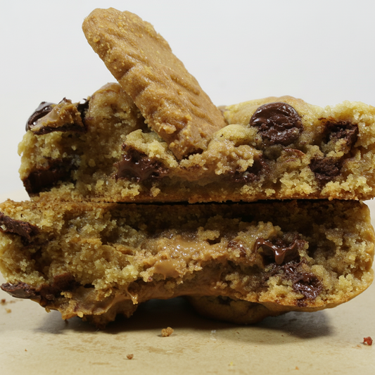 Two halves of a thick cookie butter chocolate chip cookie stacked on top of each other, with a whole cookie resting on top, photographed on a light surface against a plain light background.